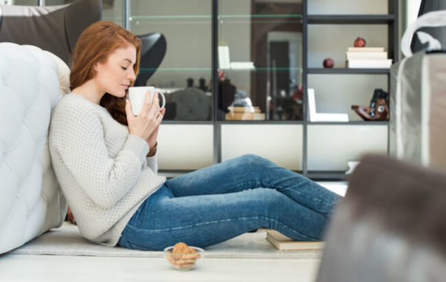 یک دختر در حال نوشیدن چای که از مزایای استفاده از عایق کاری در خانه اش لذت می‌برد. عایق کاری باعث کاهش سر و صدا می‌شود.