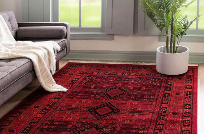یک فرش دستبافت با رنگ قرمز در دکوراسیون اتاق نشیمن. فرش دستبافت به دلیل داشتن الیاف طبیعی باید برای شستشو به قالیشویی فرستاده شود.