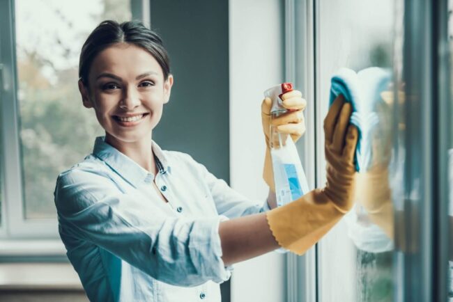 یک نظافتچی حرفه‌ای در حال انجام کار و پاک کردن شیشه