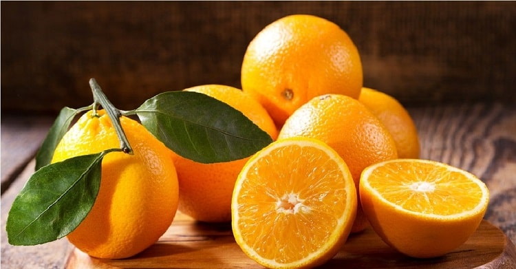  پرتقال کامل و پرتقال نصف شده که از مرکبات است 